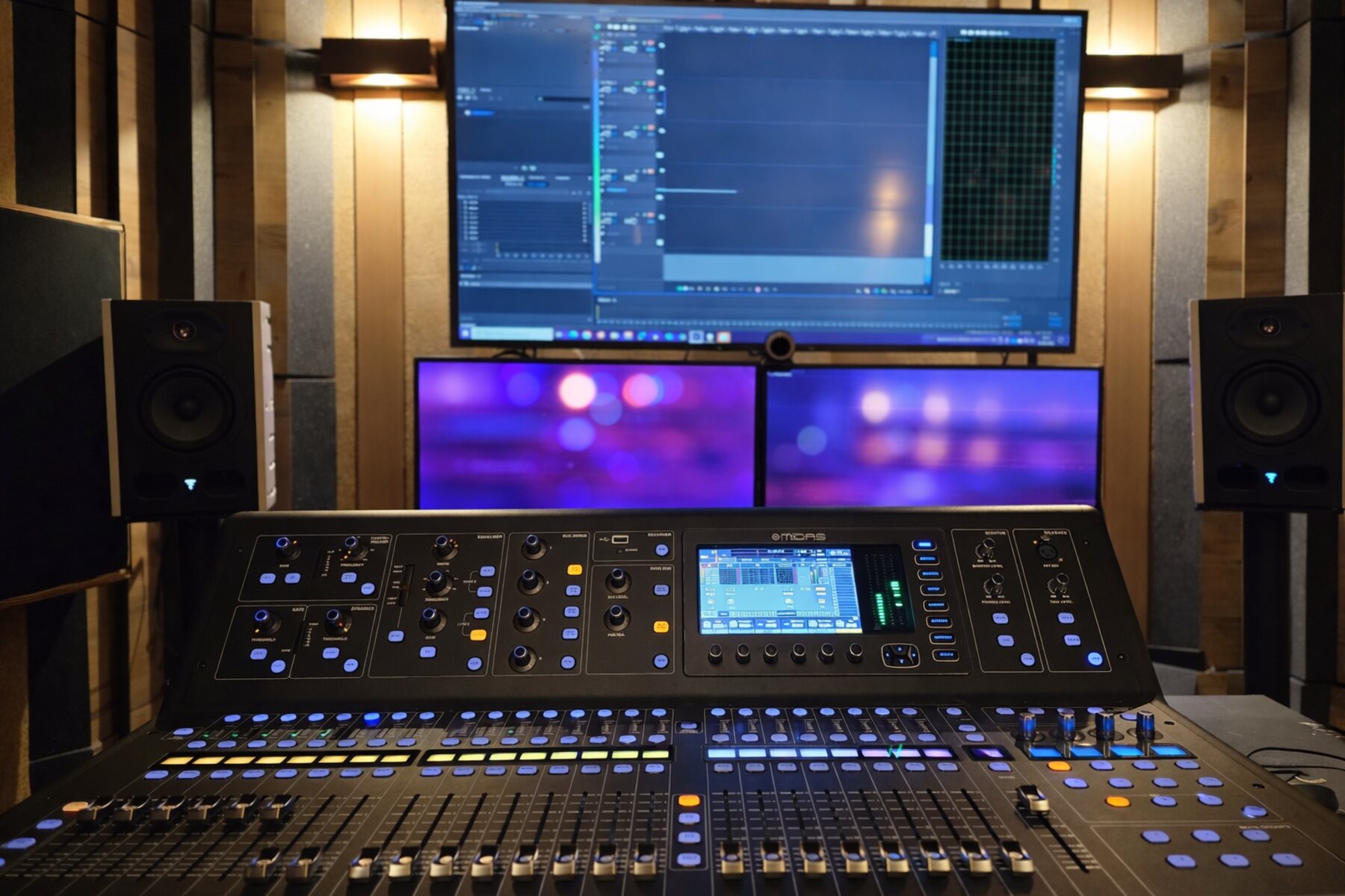 Console de mixage multipiste et écrans dans un studio son traité acoustiquement